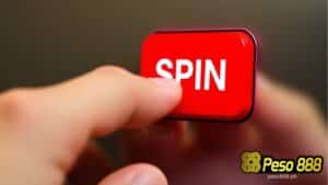 A hand presses a rectangular red button with the word SPIN on it.